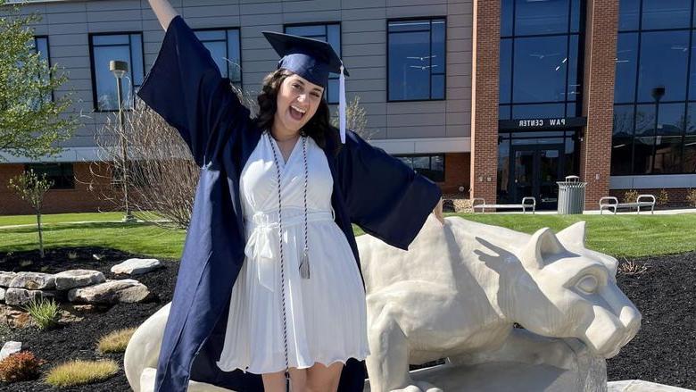 New Penn State graduate Anna Raffeinner celebrates with a joyful expression with the Lion Shrine on the Penn State 杜波依斯 campus, just outside the PAW Center